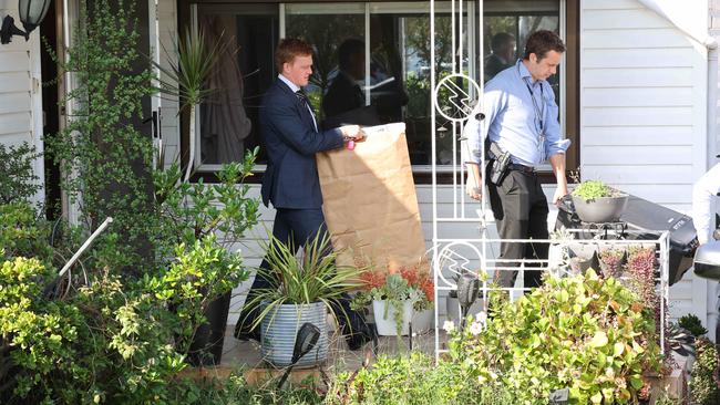 Detectives leave a house searched as part of the investigation carrying a evidence bags. Picture: Rohan Kelly