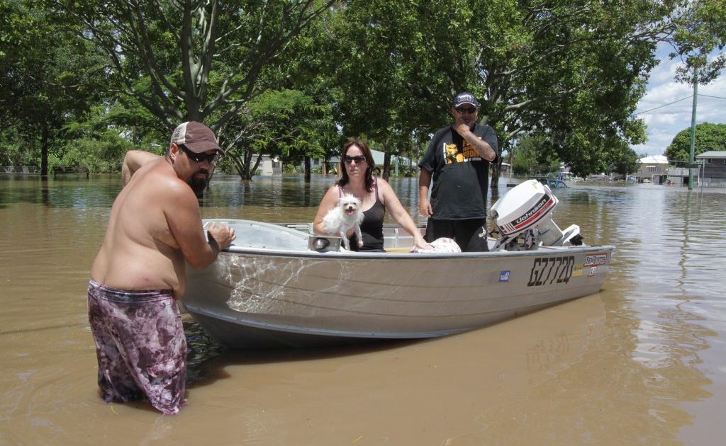 Queen St resident Liam Boase with the assistance of his friend Nathan Baker move Trish Noaln and her dog to higher and dryer ground. Picture: Robyne Cuerel