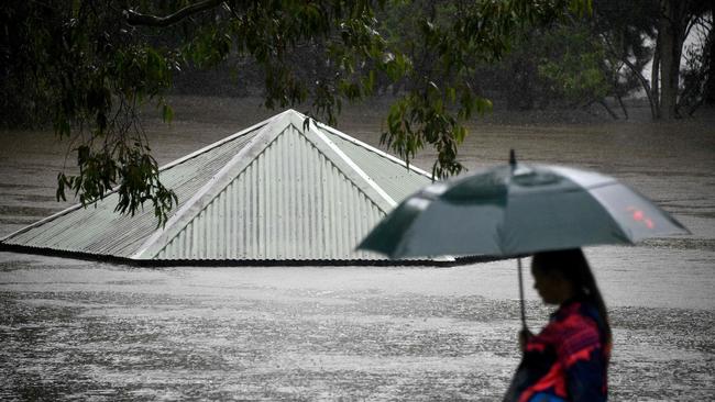 A woman walks past the Nepean River at the height of flooding on Sunday afternoon. Picture: Saeed Khan/AFP