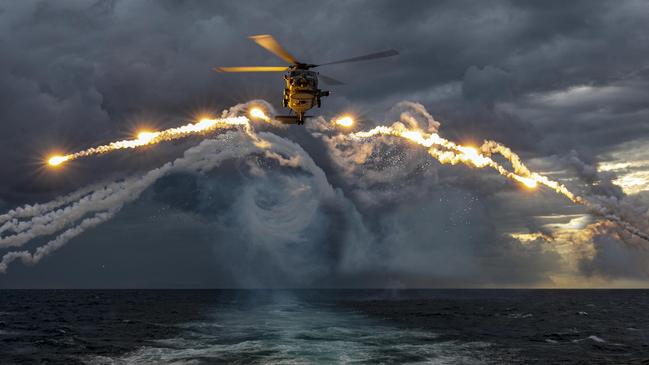 An MH-60R Seahawk helicopter embarked on HMAS Parramatta deploys Counter Measure Dispense System flares during a training flight conducted on a deployment through South East Asia. Picture: Department of Defence