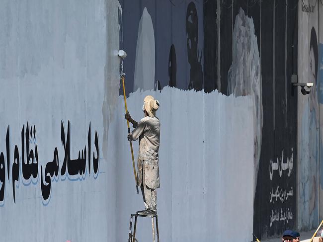 A man paints over murals on a concrete wall along a street in Kabul. Picture: AFP