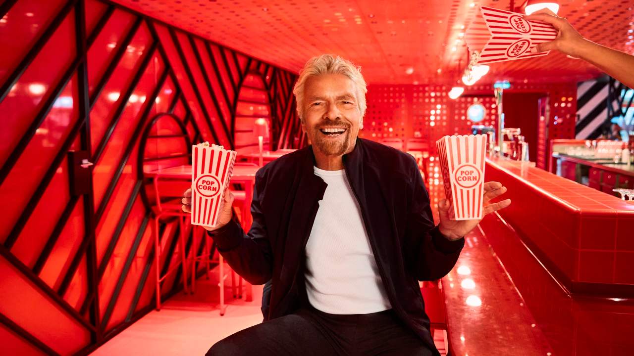 Sir Richard Branson grabbing some popcorn before a movie on one of the Virgin Voyages vessels.