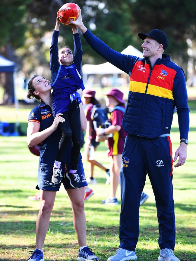 Ebony Marinoff helps Joselin from Brompton Primary School reach the lofty heights of Sam Jacobs curing the Crows Cup on Friday. Photo: Mark Brake