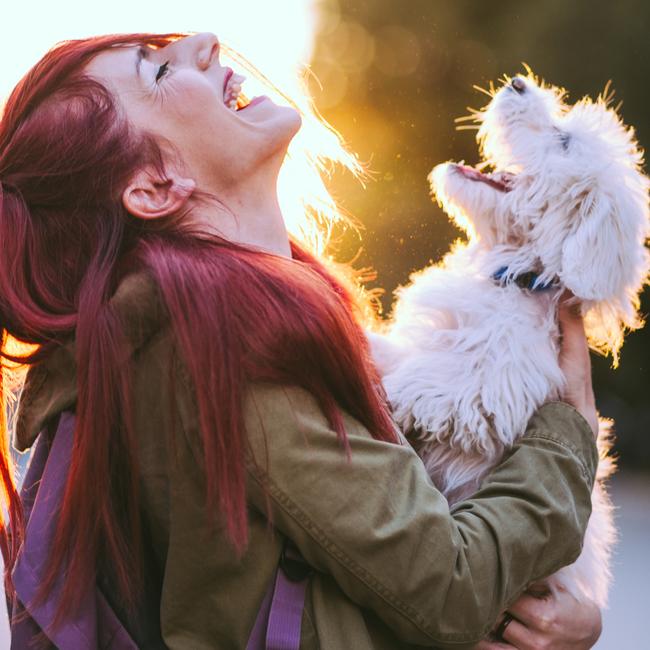 Red-headed woman and white puppy smiling together. Picture: iStock