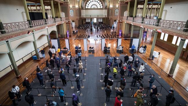 People wait to register their information before being vaccinated at the Royal Exhibition Building in Melbourne. Picture: Getty