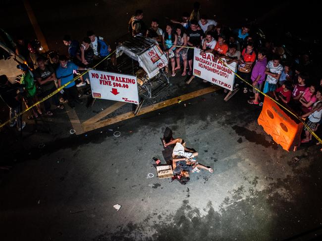 An alleged drug dealer lies dead in a Manila street next to a cardboard sign carrying his ‘confession’. Picture: Getty Images