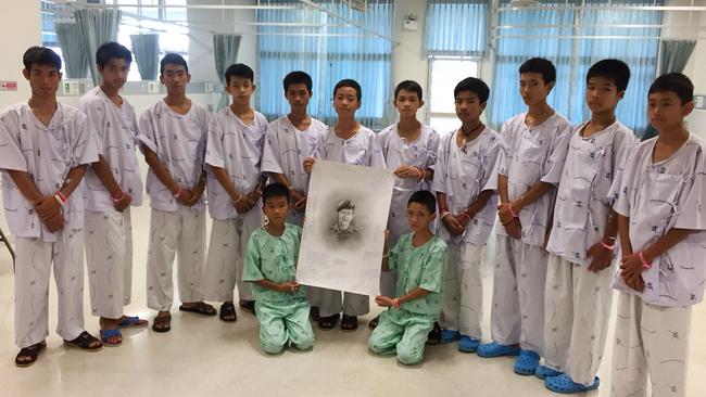 Members of the rescued Wild Boars football team pose after writing messages on a drawing of former Navy SEAL diver Saman Kunan who died during the rescue mission. Picture: AFP