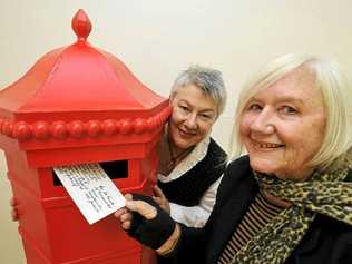 BACK IN TIME: ‘Posting’ a postcard to her 16-year-old self, Federal artist Jill Keogh, is watched by Christine Minkov, curator of the exhibition. Picture: Cathy Adams