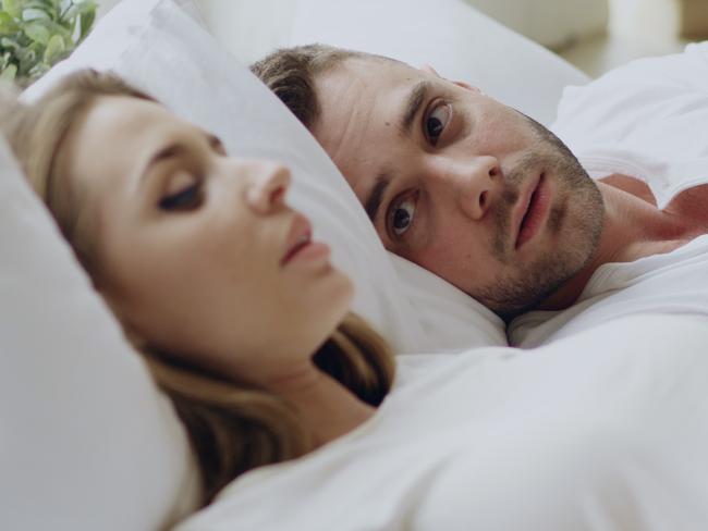 Closeup of couple with relationship problems having emotional conversation while lying in bedroom at home