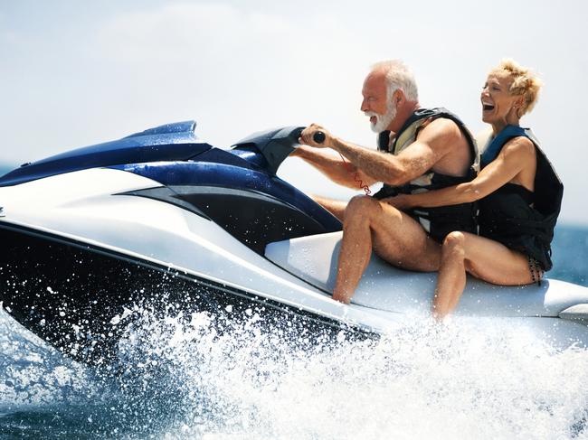 Closeup side view of a senior couple riding a jet ski on a sunny summer day at sea. Retirement, travel generic