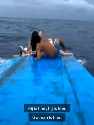 Survivors sit on the overturned boat. Picture: YouTube