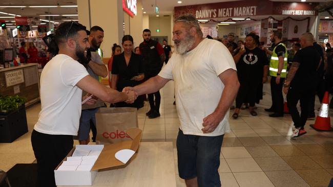 Tick Thelian, the first person in the queue at the Fairfield Coles, shakes hands with Adrian Portelli. Picture: Rohan Kelly