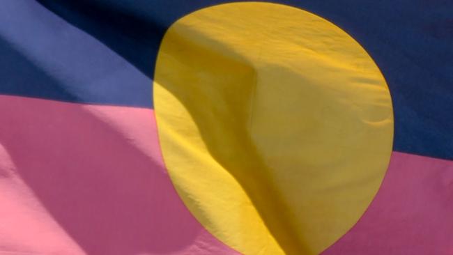 The Australian Aboriginal flag on a flagpole at Bondi Beach, Sydney, on New Year's Day 2023. This image was taken on a sunny afternoon in summer.