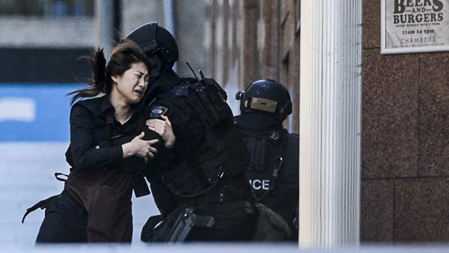 Tactical police grab a hostage as she runs from gunman Man Haron Monis. Photos: Chris McKeen