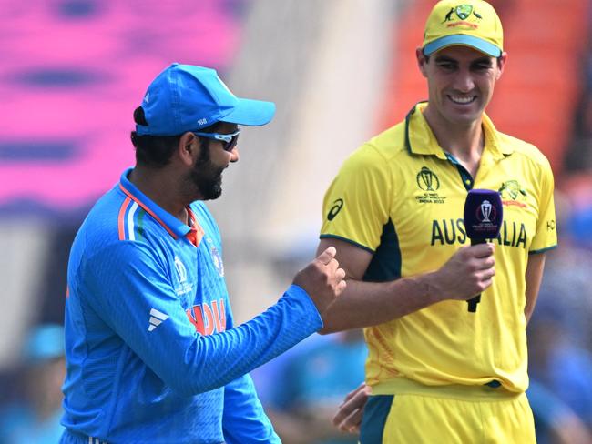 India's captain Rohit Sharma (C) and as his Australia's counterpart Pat Cummins (R) gesture during the toss before the start of the 2023 ICC Men's Cricket World Cup one-day international (ODI) final match between India and Australia at the Narendra Modi Stadium in Ahmedabad on November 19, 2023. (Photo by Sajjad HUSSAIN / AFP) / -- IMAGE RESTRICTED TO EDITORIAL USE - STRICTLY NO COMMERCIAL USE --