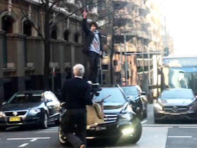 Alleged killer Mert Ney wields a knife as he stands on top of a car in Sydney's CBD. Picture: 7 News