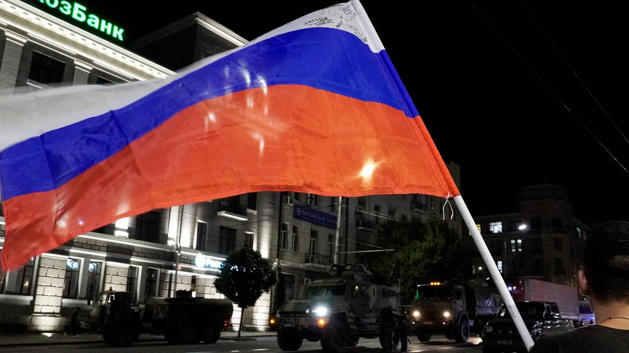A man waves the Russian national flag as the members of Wagner group prepare to pull out from the headquarters of the Southern Military District to return to their base in Rostov-on-Don. Picture: Stringer/AFP