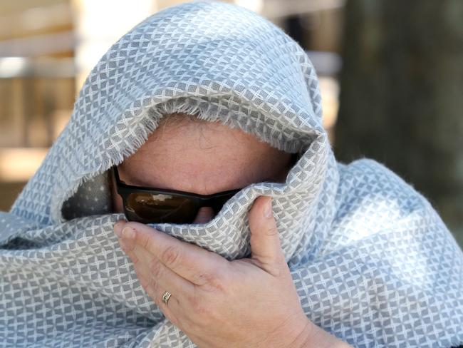 Helena Heaft covers her face as she leaves the Adelaide Magistrates Court in Adelaide, Friday, October 11, 2019. (AAP Image/Kelly Barnes) NO ARCHIVING