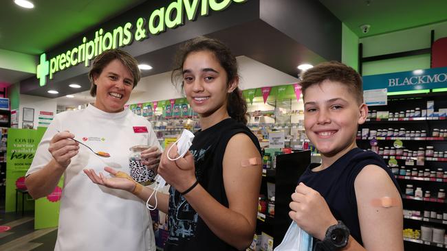 Managing Pharmacist Kathy Myers with jelly beans for Tara Breusch, 12, of The Gap, and Archie Beak, 12, from Mount Ommaney, after they received a Moderna jab Priceline Pharmacy on George Street, Brisbane. Picture: Liam Kidston