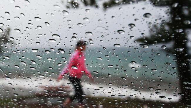 A walker doesn't mind the rain at Burleigh Heads on the Gold Coast. Picture: Luke Marsden/file