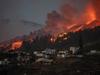 A river of lava approaches houses as Mount Cumbre Vieja erupts in El Paso, spewing out columns of smoke, ash and lava as seen from Los Llanos de Aridane on the Canary island of La Palma on September 19, 2021. - The Cumbre Vieja volcano erupted on Spain's Canary Islands today spewing out lava, ash and a huge column of smoke after days of increased seismic activity, sparking evacuations of people living nearby, authorities said. Cumbre Vieja straddles a ridge in the south of La Palma island and has erupted twice in the 20th century, first in 1949 then again in 1971. (Photo by DESIREE MARTIN / AFP)