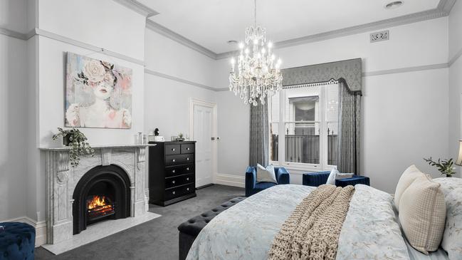 An open fireplace with marble mantel features in the spacious main bedroom.