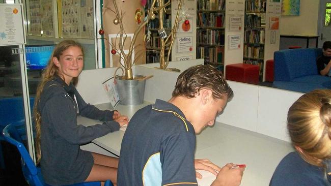 SIMPLE ACT OF KINDNESS: Students fill out the Christmas cards in the school library, which has been decked out like a Christmas village. Picture: Contributed