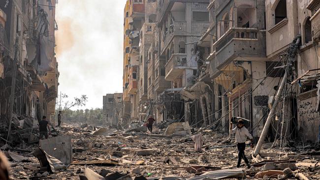 man carries a propane gas cylinder on his back while walking through debris and destruction littering a street in the Jabalia camp for Palestinian refugees in Gaza City. Picture: AFP