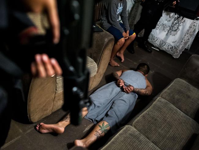 A suspected gang member is handcuffed and laid on the floor by police in El Salvador. Picture: Jan Sochor/Rex Features.