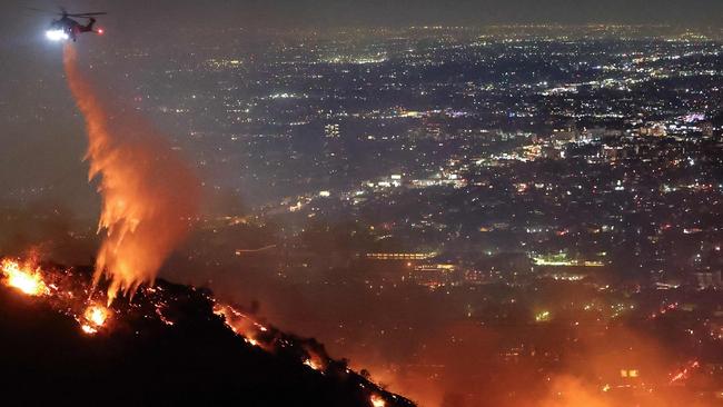 A firefighting helicopter drops water as the Sunset Fire burns in the Hollywood Hills. Picture: Getty Images via AFP