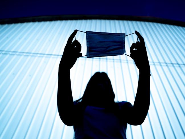 Silhouette of a Young Woman Holding Protective Face Mask in Hands Outdoors. Picture: CasarsaGuru