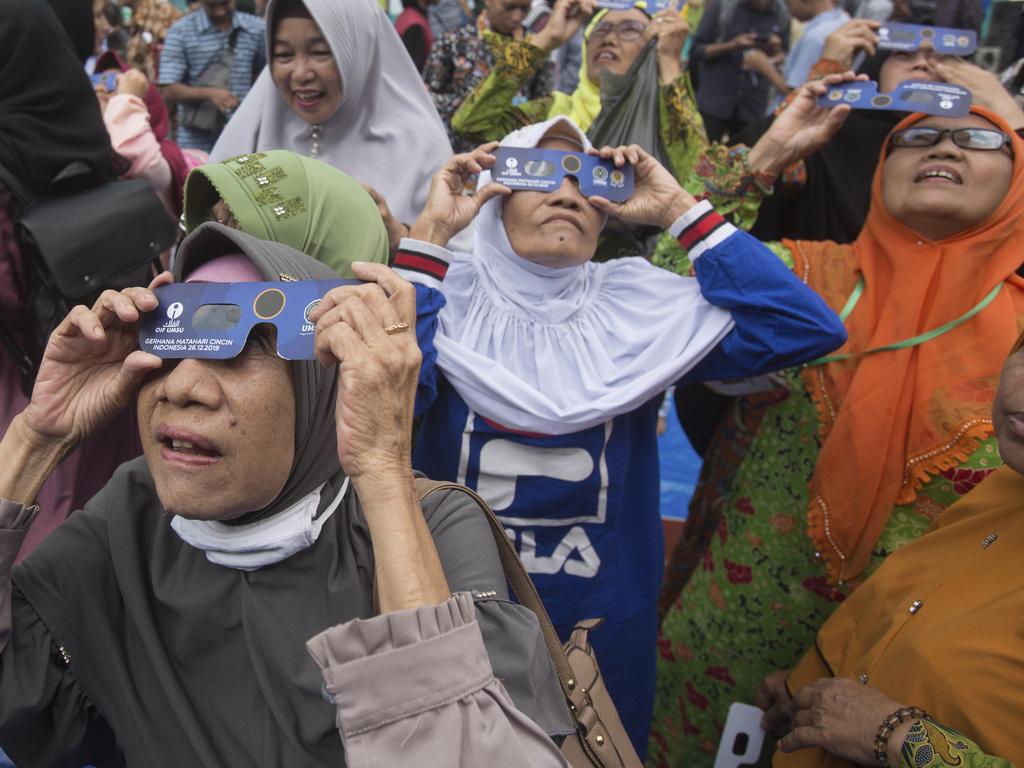 Women watch a solar eclipse through special glasses in Medan, Indonesia. Picture: AP