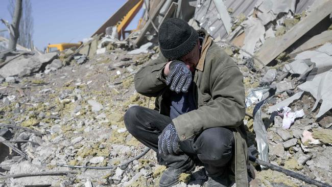 A man helps Ukrainian soldiers searching for bodies in the debris at the military school hit by Russian rockets the day before, in Mykolaiv, southern Ukraine. Picture: AFP