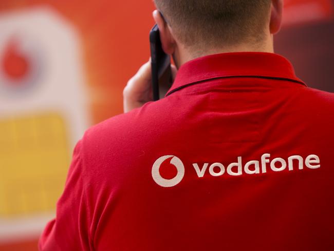 The Vodafone Group Plc logo sits on the back of an employee's shirt as speaks on a mobile handset inside the company's Oxford Street store in London, U.K., on Monday, April 8, 2013. Vodafone Group Plc is restating its results going back two fiscal years as new international accounting rules for joint ventures cut historical revenue and earnings. Photographer: Simon Dawson/Bloomberg