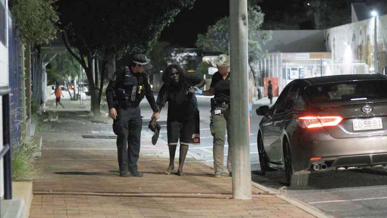 A woman is helped by police on the streets of Alice Springs.