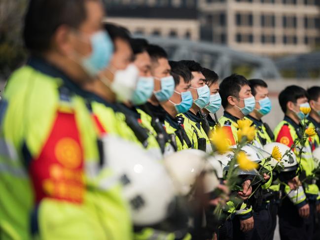 Chinese policemen wear protective masks during a national mourning to mourn victims of COVID-19 at Shanghai People's Heros Memorial Tower in Shanghai, China. Picture: Getty