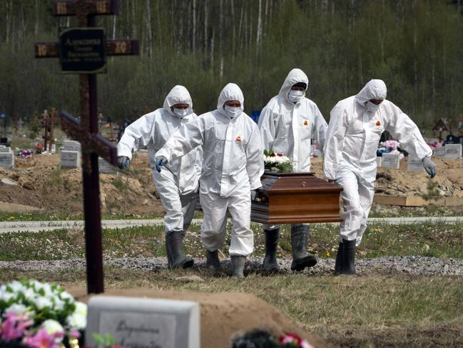 Gravediggers in protective suits carry the coffin of a COVID-19 victim as relatives and friends stand at a distance in the section of a cemetery reserved for coronavirus victims in Kolpino, outside St. Petersburg, Russia. Picture: AP