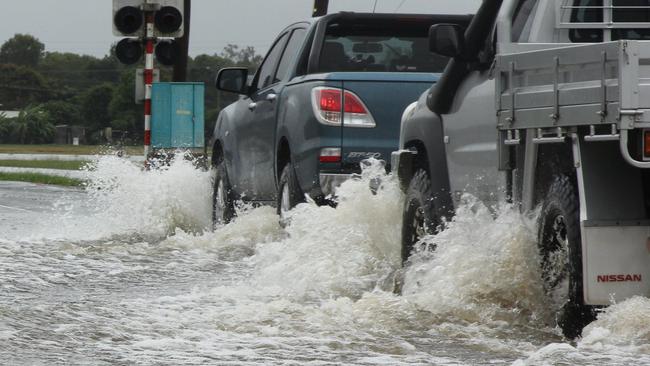 Cars navigate Hamilton Plains on Shute Harbour Rd after it became officially closed to traffic because of flooding.