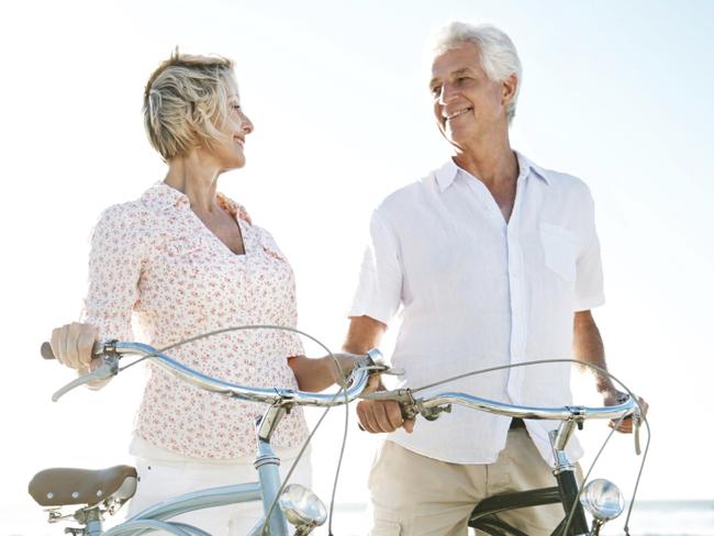 Two active seniors with their bicycles on the beach