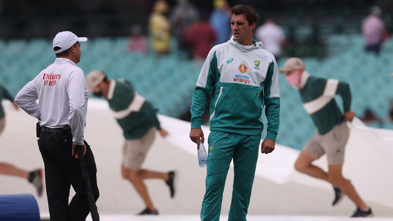 Australia captain Pat Cummins talks to an official as groundsmen take off covers the SCG pitch. Picture: David Gray/AFP