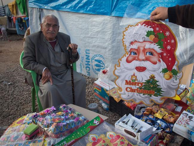 Black market ... An Iraqi Christian, who fled from his home because of Islamic State's advance earlier this year, sells Christmas decorations at the entrance to a camp near Umm al-Nour Church, which is now home to hundreds of displaced Iraqi Christians. Source: Getty