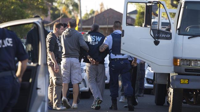 The man is led away by police after his arrest on Colechin St, Yagoona.