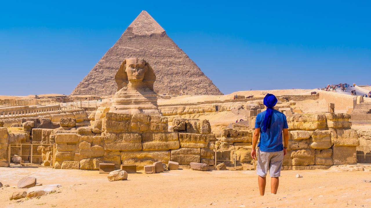 A young man walking towards the Great Sphinx of Giza and in the background the pyramid of Khafre, the pyramids of Giza. Cairo, Egypt