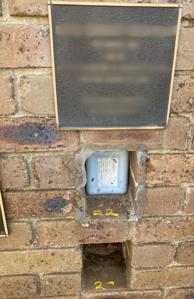 Containers filled with ashes were left exposed after thieves ripped metal plaques sealing the holes in the brick wall.