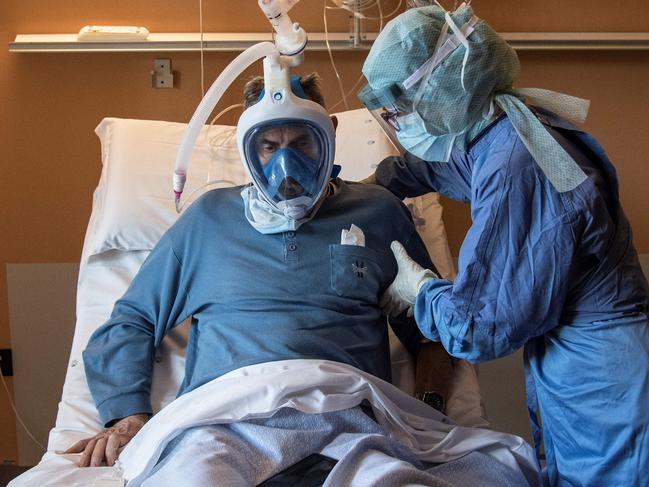 TOPSHOT - A nurse helps a patient suffering from COVID-19 who uses the Decathlon snorkeling face mask in the COVID ward of the Maria Pia Hospital in Turin on April 7, 2020. - This private facility converted into a COVID hospital is the first to use snorkeling mask from Decathlon as CPAP (Continuous Positive Airway Pressure) for patients suffering from novel coronavirus (COVID-19). (Photo by MARCO BERTORELLO / AFP)