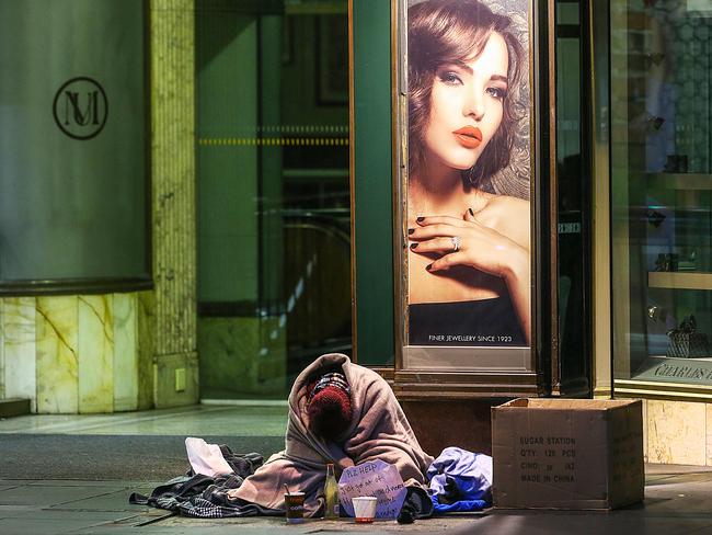 A man sleeps on the path in Swanston Street opposite the Melbourne Town Hall. Picture: Ian Currie