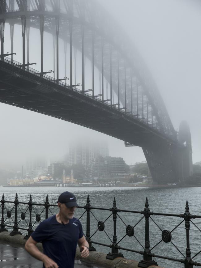 The Harbour Bridge is seen just peering through the fog. Picture: NCA NewsWire / Damian Shaw