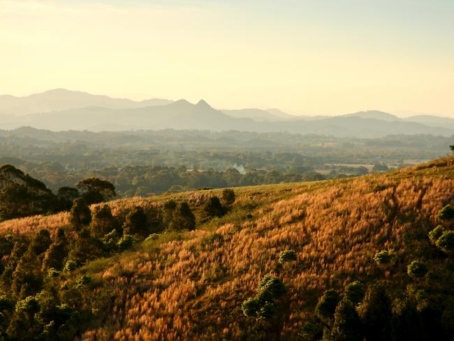 Horizontal landscape of the mountains, hills and plains of the Byron Bay Shire on the north coast of NSW. Late afternoon sunshine lights up the rainforests.