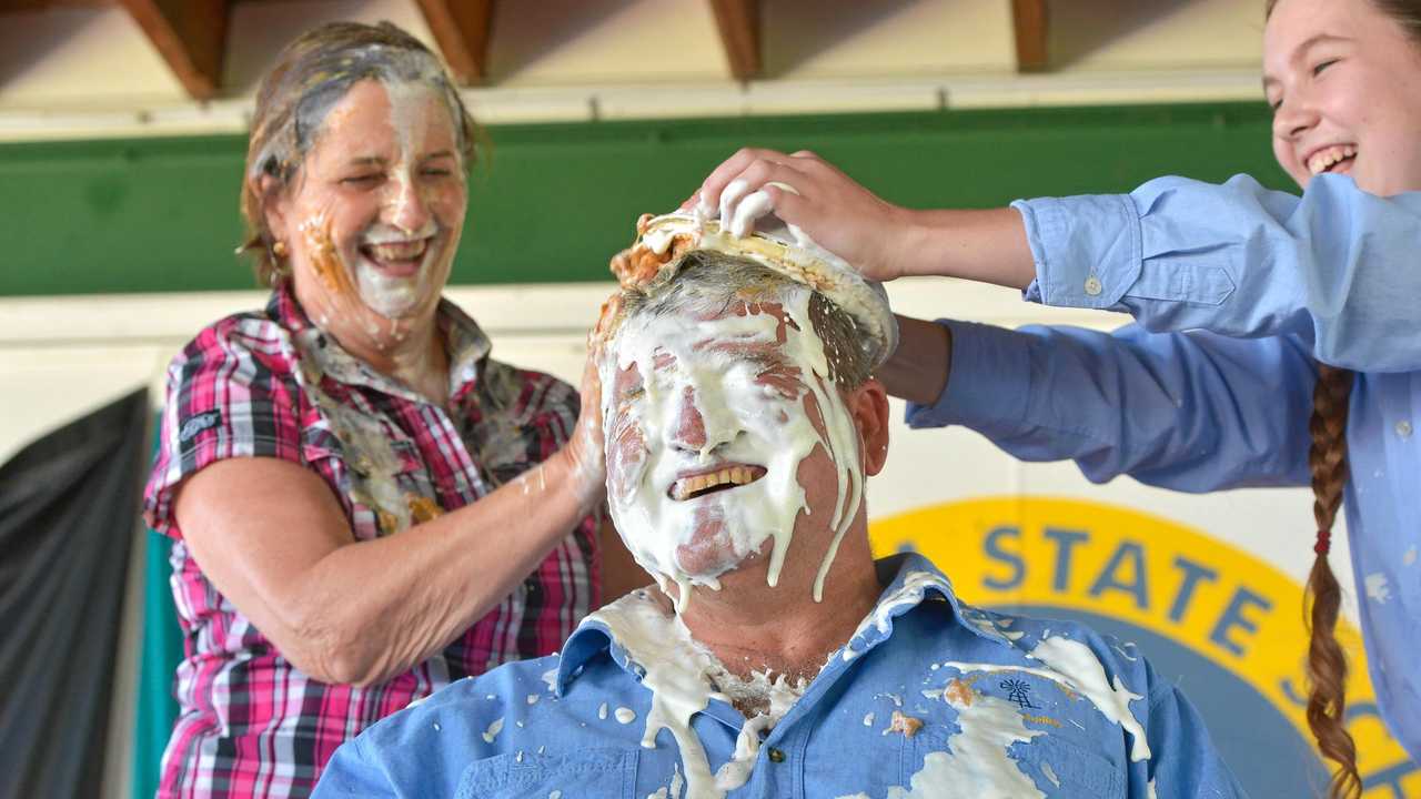 CREAMED: Mt Larcom State School principal Pauline Porch and student Shalom White have a laugh as teacher Norm Horan cops a caramel cream pie in the face. The school helped raise money for drought relief. Picture: Mike Richards GLA140918PIEF