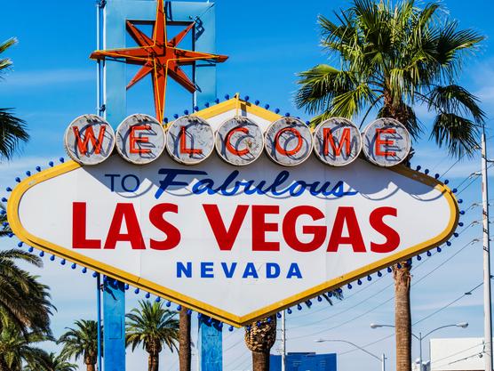 Photo of the famous Las Vegas sign with many hotels and lights on background.